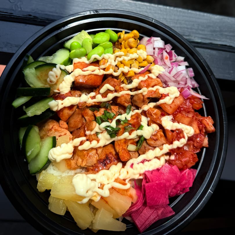 Korean-fusion poke bowl with chicken, edamame, corn, red onions, kimchi, pineapple, and pickled radish.